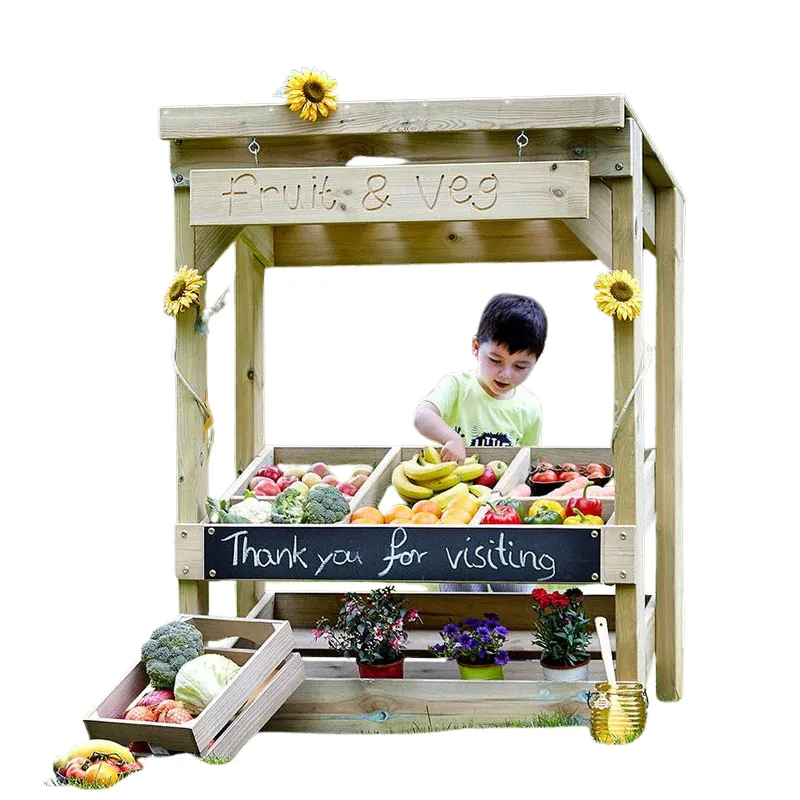 Child playing in outdoor market stall role play station with fruits and cash register in preschool dramatic play setup