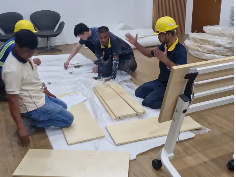 Singapore-based support team assembling and maintaining kindergarten furniture with safety helmets