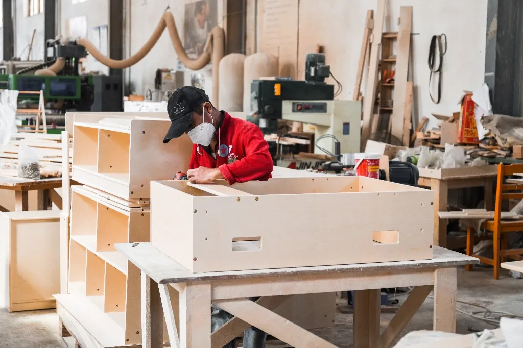 Factory worker fastening a birch preschool storage unit on the assembly bench
