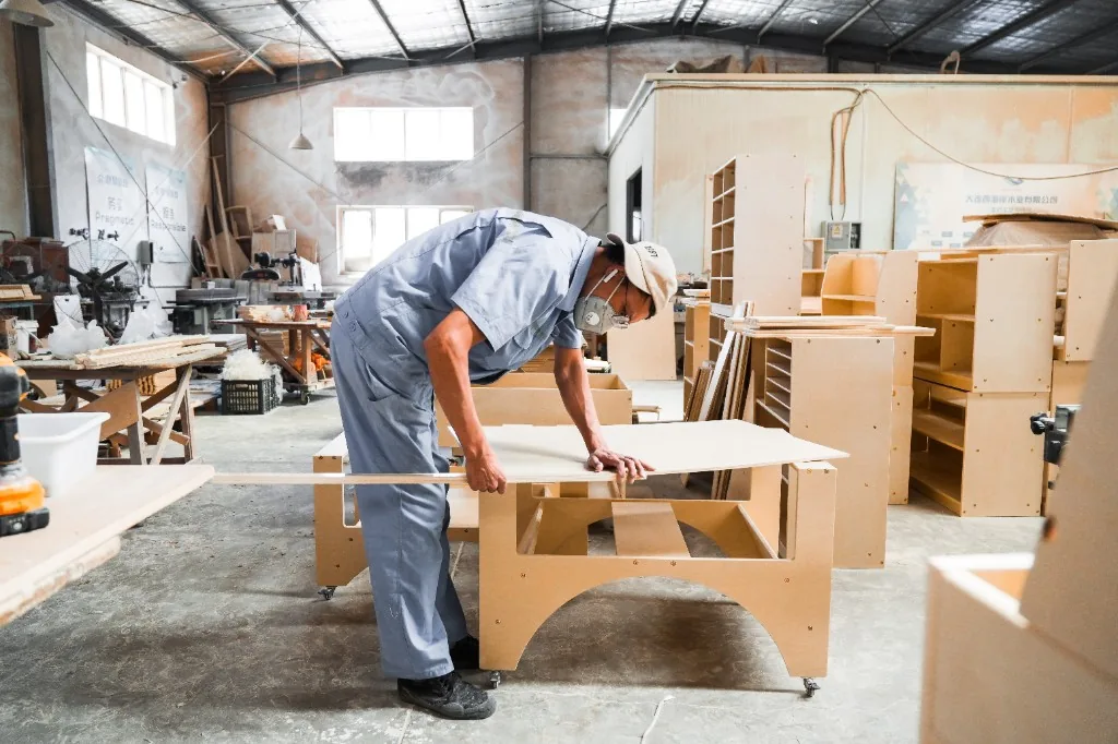 Factory worker checking a birch preschool table during assembly