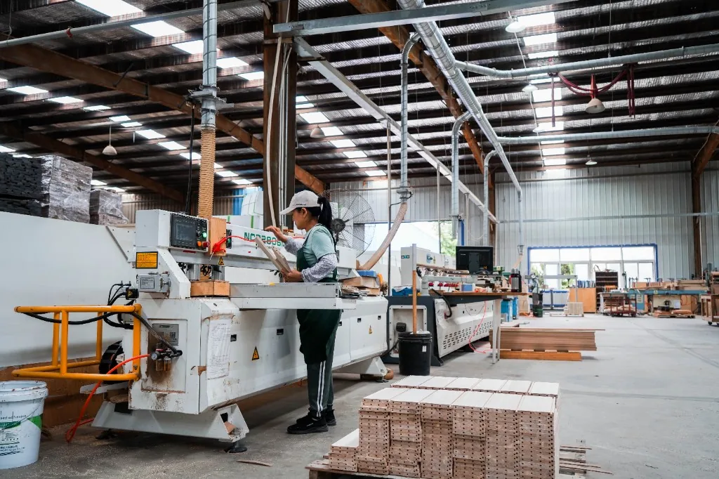 Operator running an edge-banding machine on a plywood rail at West Shore in Dalian