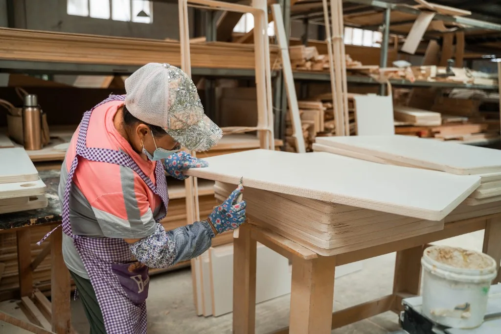 Worker inspecting the edge of a white laminate preschool table before packing
