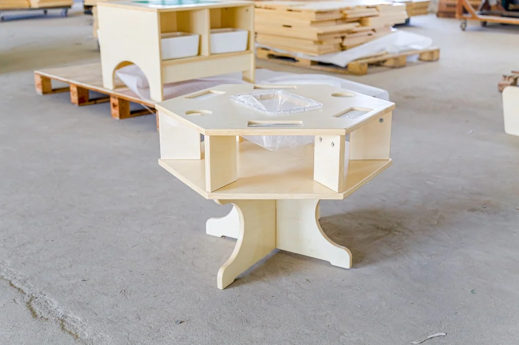 Hexagonal birch preschool art table with paint-cup holes and a centre bin