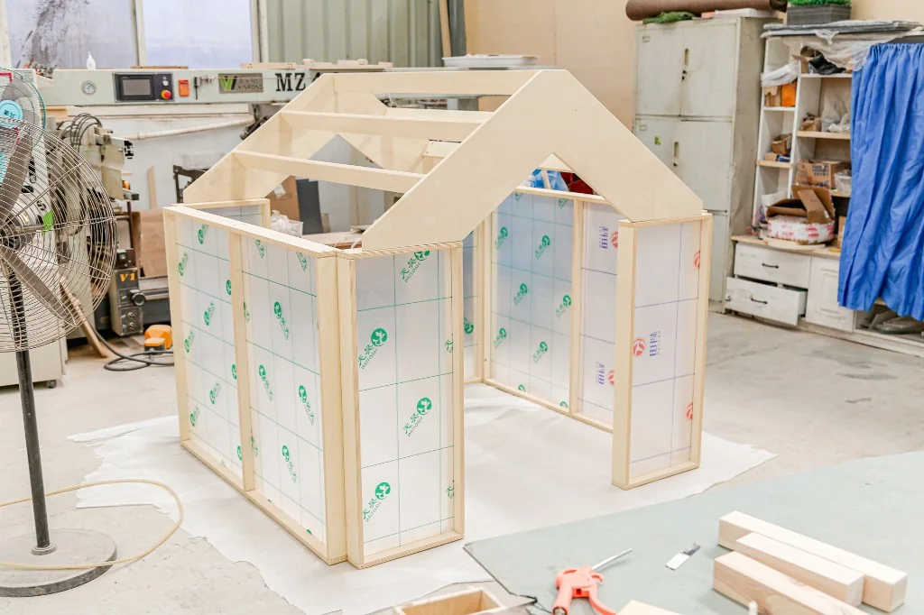 Wooden playhouse frame with acrylic panels being built in West Shore factory